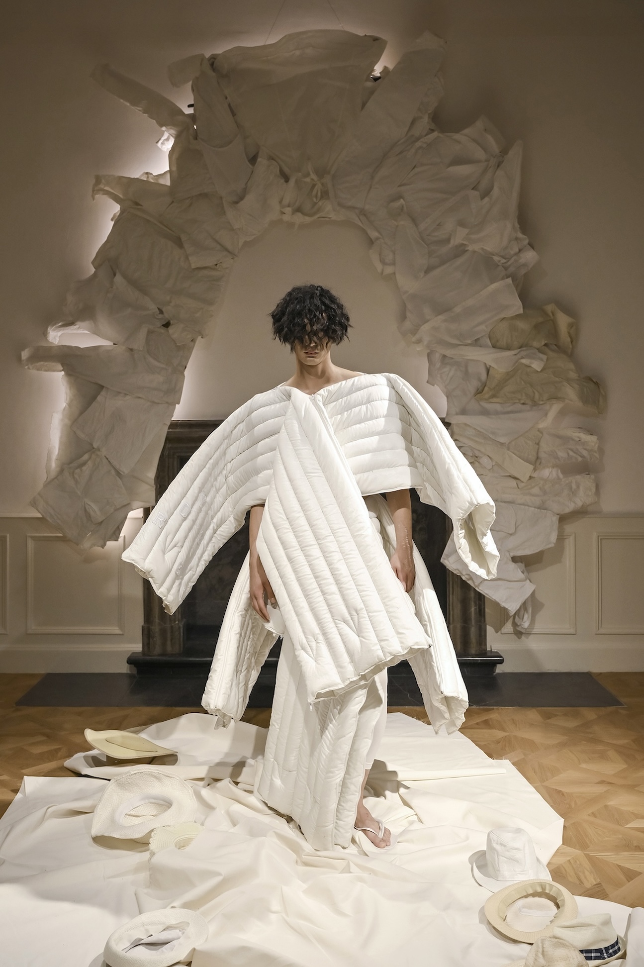 A performer extends the pleated sections of a white garment during ANTICON.