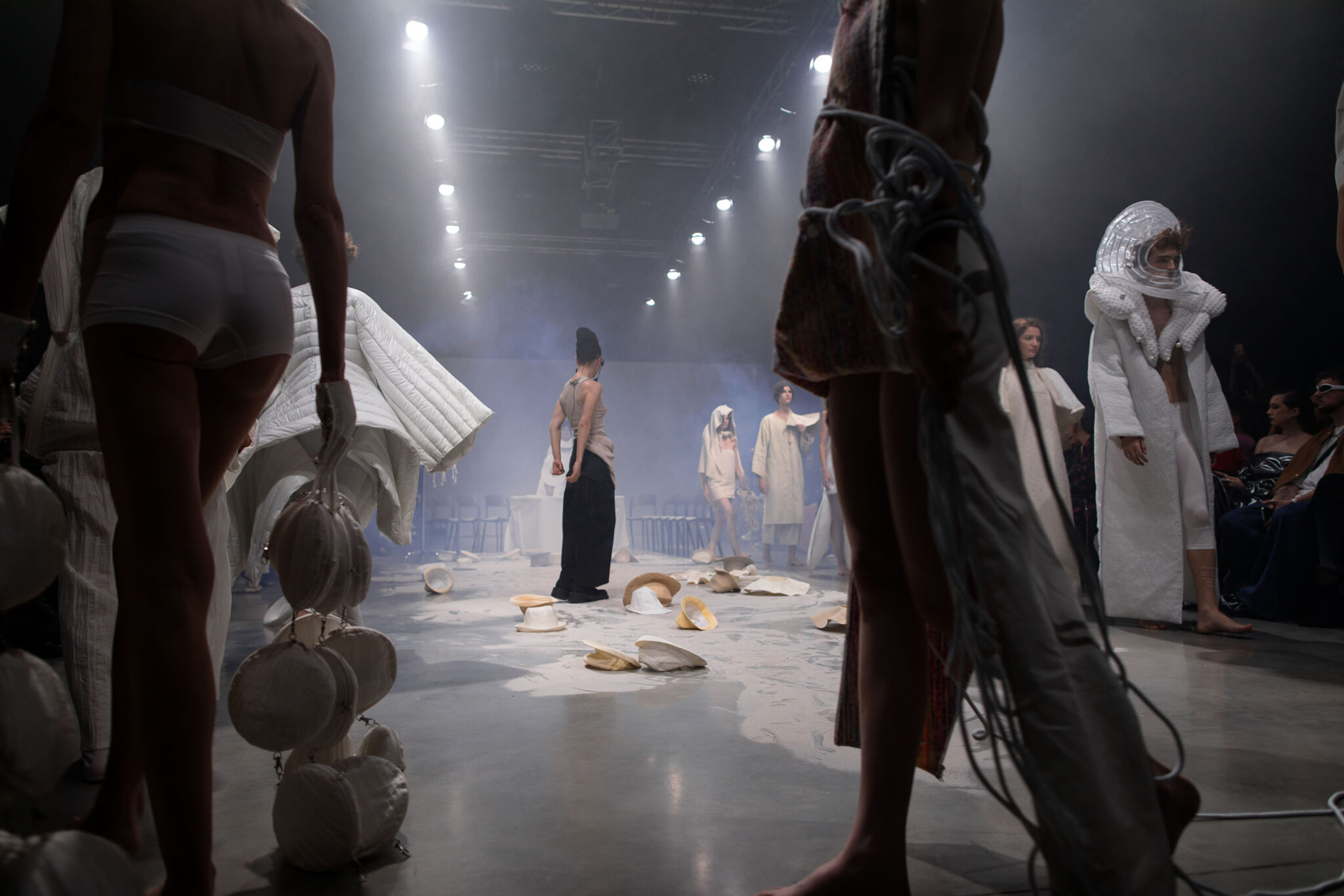 A wide stage view shows performers among tables, fabric and hanging objects during ANTICON.